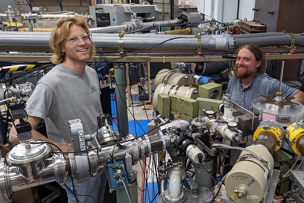 Scott Haselschwardt (LBNL) and Tim Daniels (UNC Wilmington) with the experimental setup – four high-purity germanium detectors surrounding the target chamber – at the end of the Triangle Universities Nuclear Laboratory beamline. Photo: Sean Finch.