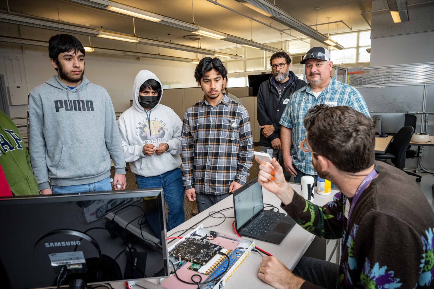 Keith Penney (seated), an electronics engineer in the Advanced Technologies Group, introduced students to low-level RF controls of accelerating cavities, while Sean Spillane and Gabor Paulovits (top right) look on. (Photo by Thor Swift, Berkeley Lab)