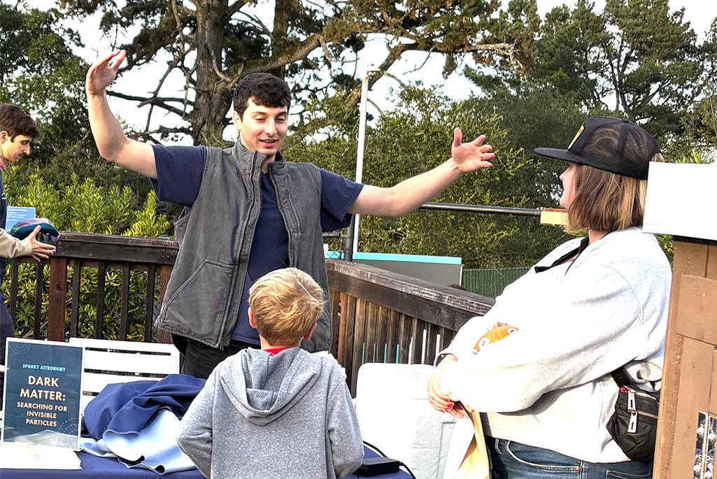 Dan Kodroff shows a young visitor the vast unknown scale of dark matter masses. Credit: Emily Perry, Berkeley Lab