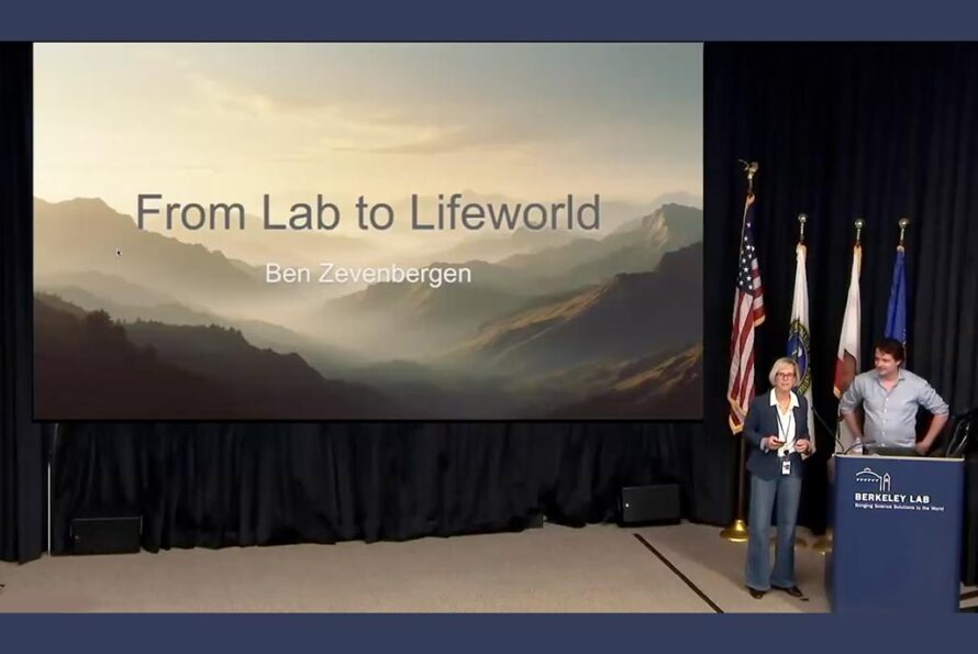 Natalie Roe introducing Ben Zevenbergen at the podium, in front of a screen on which is projected Ben's initial slide with the title of his talk.