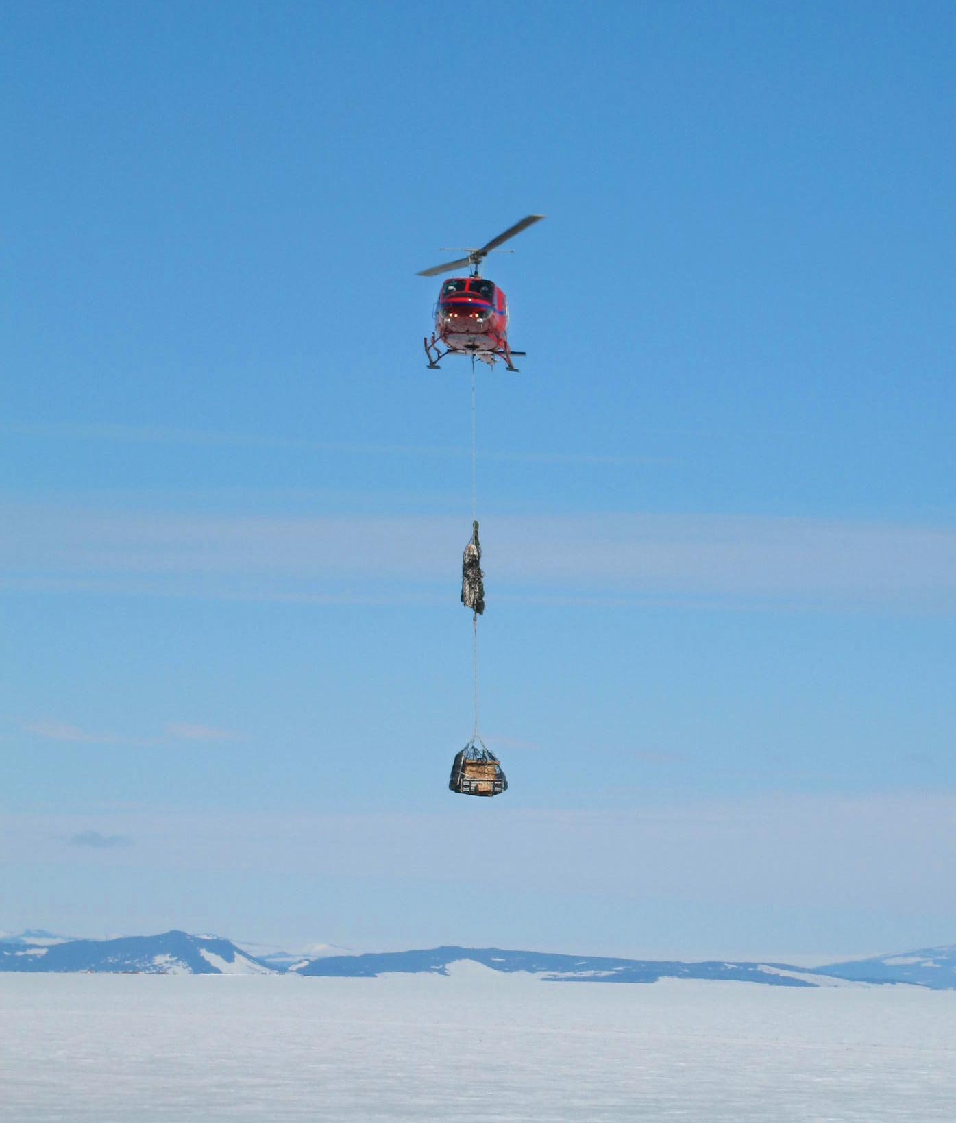 A helicopter with a sling load brings scientific equipment to Stezelberger and Klein’s camp site on the Ross Ice Shelf in Antarctica. Credit: Spencer Klein, Berkeley Lab