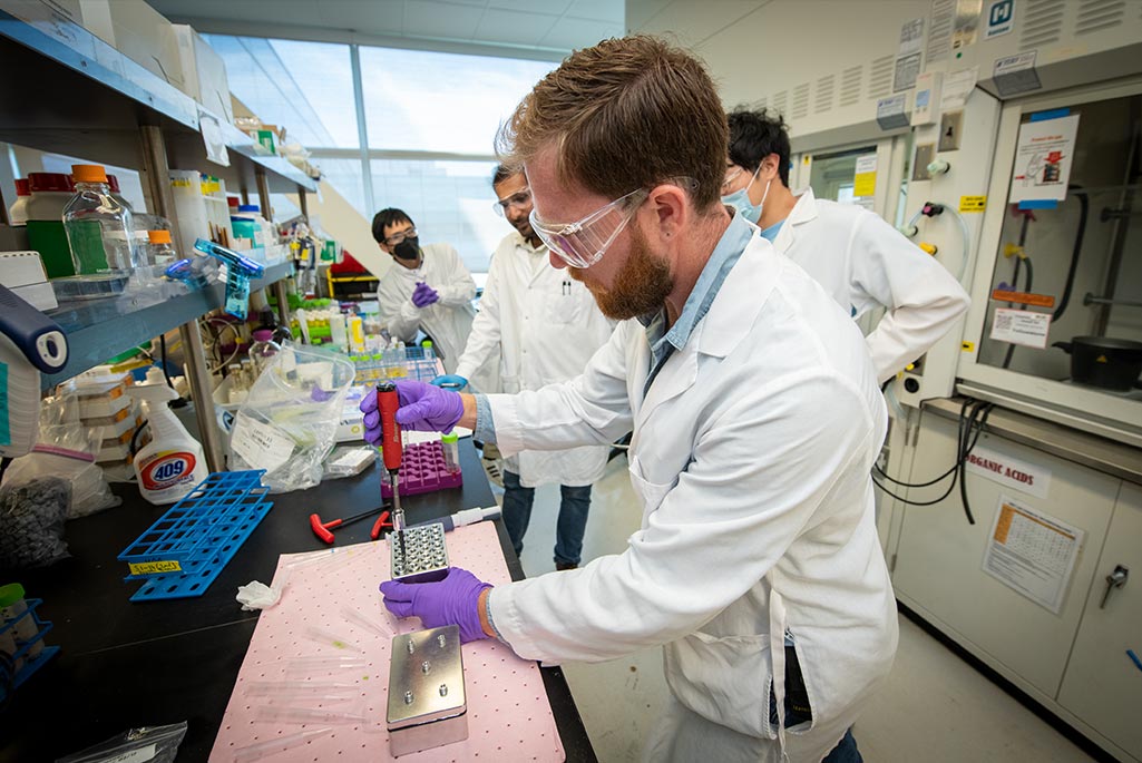 Mechanical Engineer Nick Wenner, a member of the Engineering Small Project Support team, demonstrates the method for sealing each well in the small high-throughput pressure reactor he designed and built for use in specialized experiments. Credit: Thor Swift, Berkeley Lab