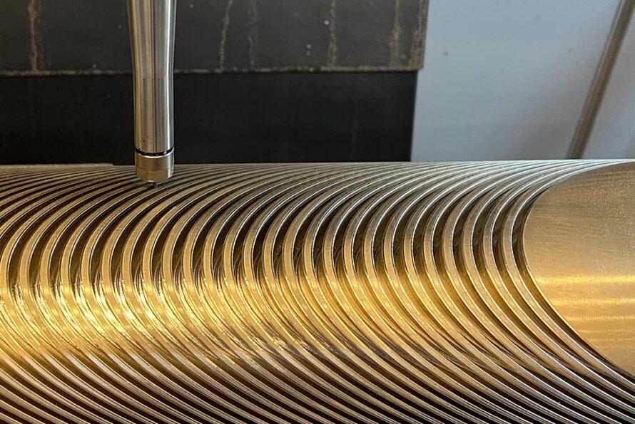 A computer numerical control (CNC) machine in Berkeley Lab Engineering’s building 77 traces the intricate pattern of a groove for a superconducting cable into an aluminum bronze mandrel. Credit: Bun Pa Lim, Berkeley Lab