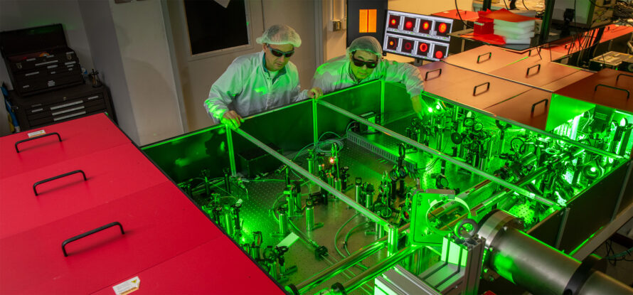 Hai-En Tsai and Jeroen van Tilborg inspect the optical table that houses the high-power laser amplifier at the Berkeley Lab Laser Accelerator Center. (Credit: Robinson Kuntz/Berkeley Lab)