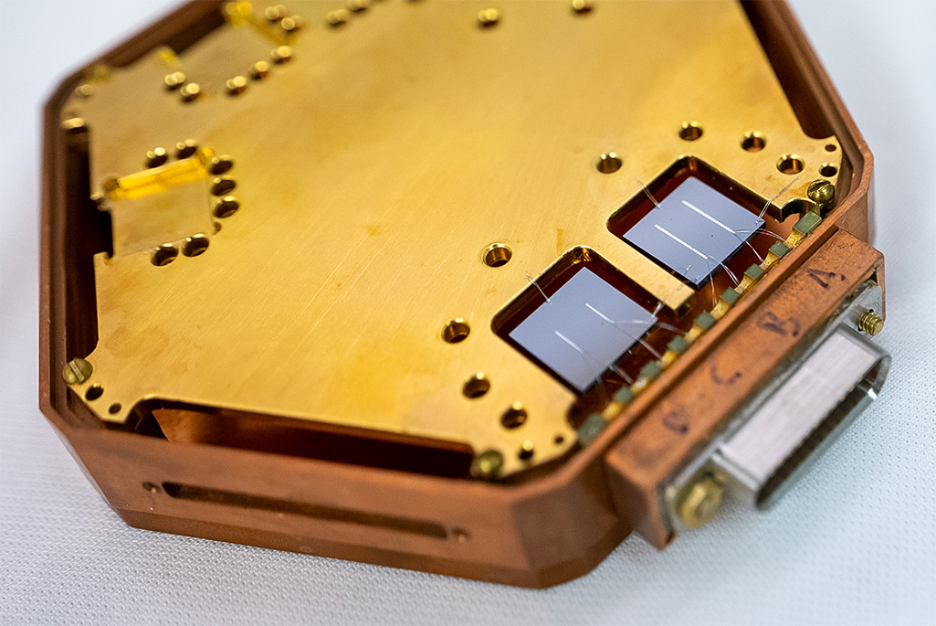 Alt text: Close-up of a hexagonal structure holding two square chips, each with two reflective lines.