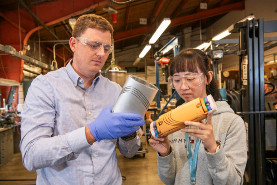 ATAP researchers Lucas Brouwer (left) and Yufan Yan examine prototypes of ecliptic aperture canted-cosine-theta magnets, capable of producing dipole or quadrupole magnetic fields. (Credit: Robinson Kuntz, Berkeley Lab)
