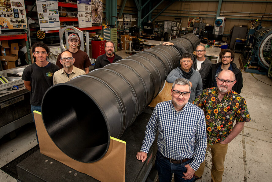 The ATLAS Pixel Support Tube builders and fabricators, photographed next to the Pixel Support Tube, in the Engineering Division's Mechanical Fabrication Shops (April 24, 2026) - Credit: Thor Swift, Berkeley Lab