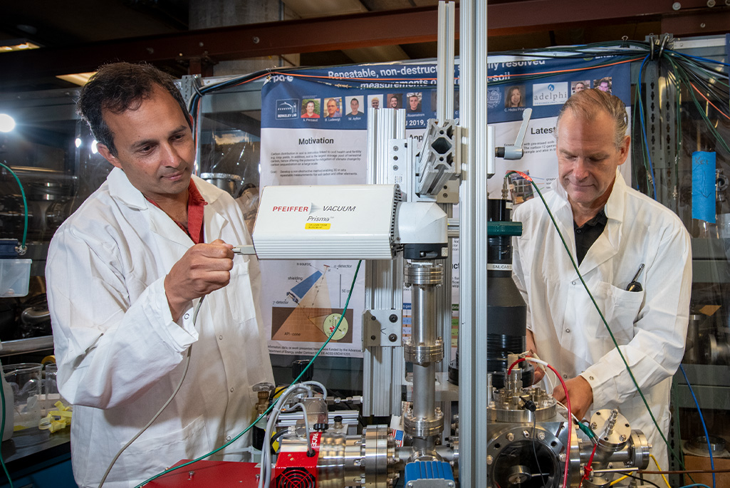 The ATAP Division's Arun Persaud (left) and Thomas Schenkel study fusion reaction rates in materials at Berkeley Lab. Credit: Thor Swift, Berkeley Lab. Alt text: Two people in lab coats adjust equipment.