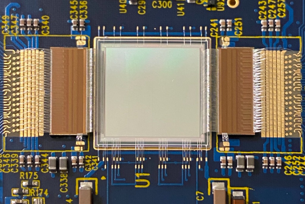 An image sensor and two custom readout chips for the VeryFastCCD project. These components were designed at Berkeley Lab and wire bonded together in the Engineering Division. The unusual design of these pieces means that the sensor is wire bonded directly to the readout chips on both sides rather than the more traditional method of being bonded to the printed circuit board. (Credit: Phathakone Sanethavong, Berkeley Lab)