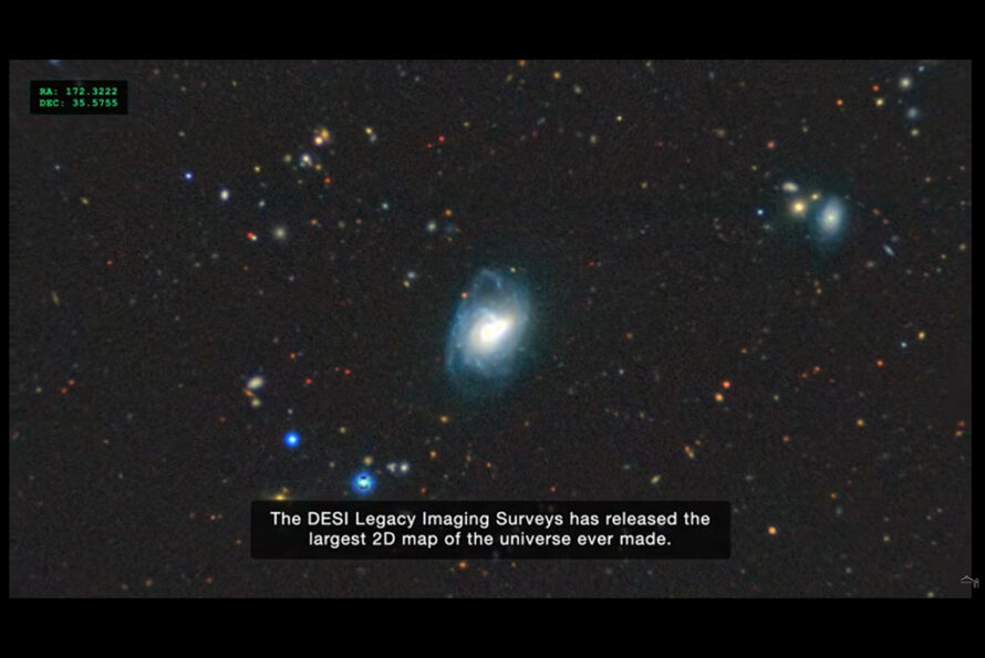 A screenshot from the video showing a black background with dots and smudges of various sizes and colors that indicate the celestial objects observed in the newest DESI Legacy Survey, and a caption at the bottom that reads, "The DESI Legacy Imaging Surveys has released the largest 2D map of the universe ever made."