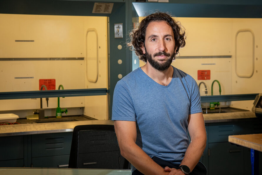ALT: A researcher wearing a blue T-shirt sits in a research lab.